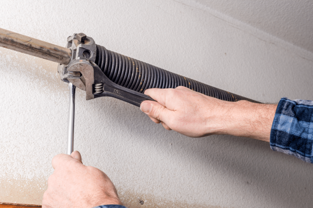 A man uses a wrench while performing an emergency garage door repair.