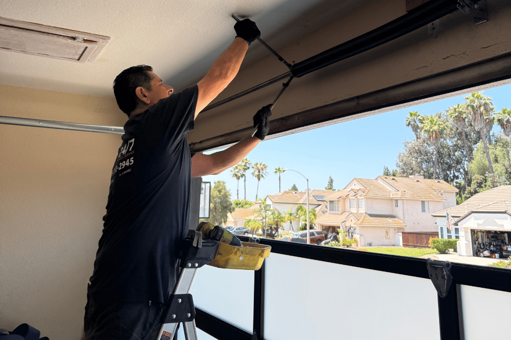 A man repairs a large garage door installation, highlighting the importance of garage door service prices in San Diego for home maintenance.